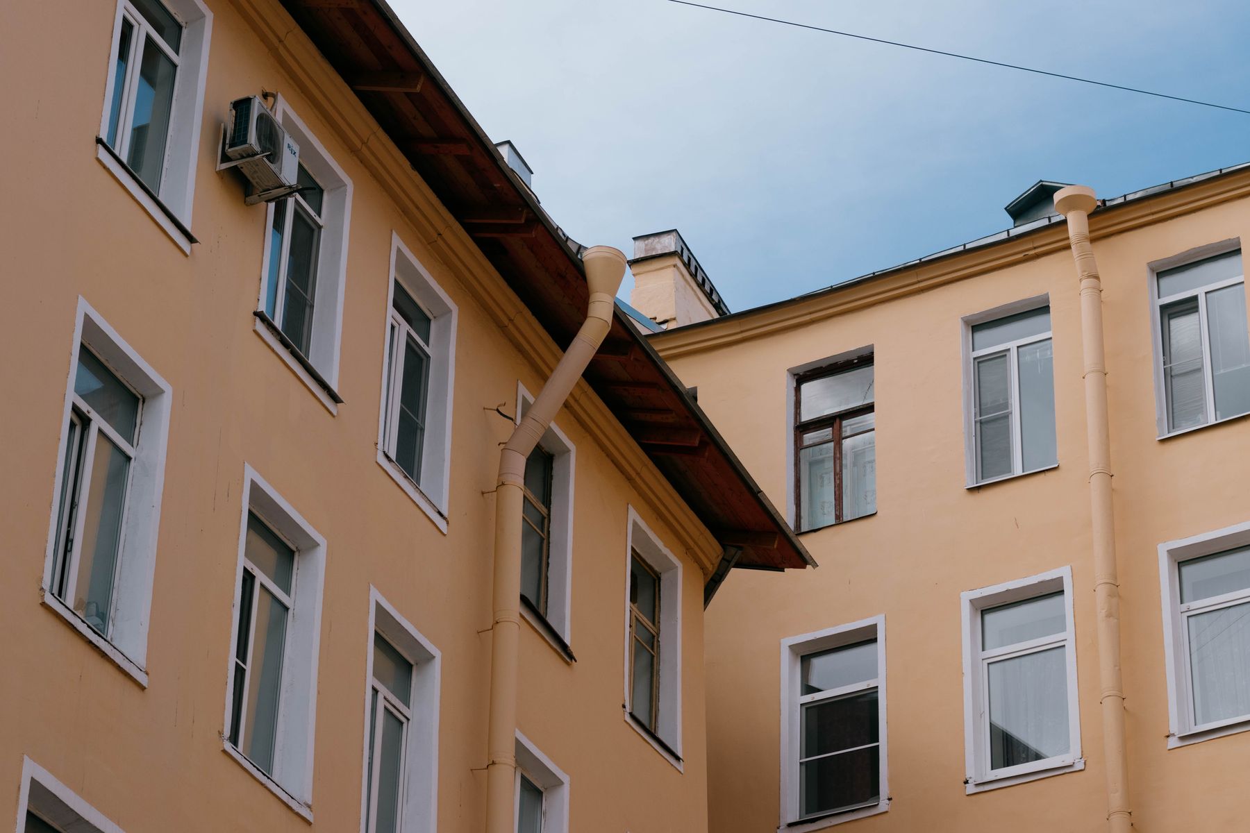 Fallrohr an einer Hausfassade vor blauem Himmel