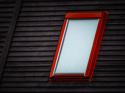 Rot gerahmtes Dachfenster in einer dunklen Holzverkleidung