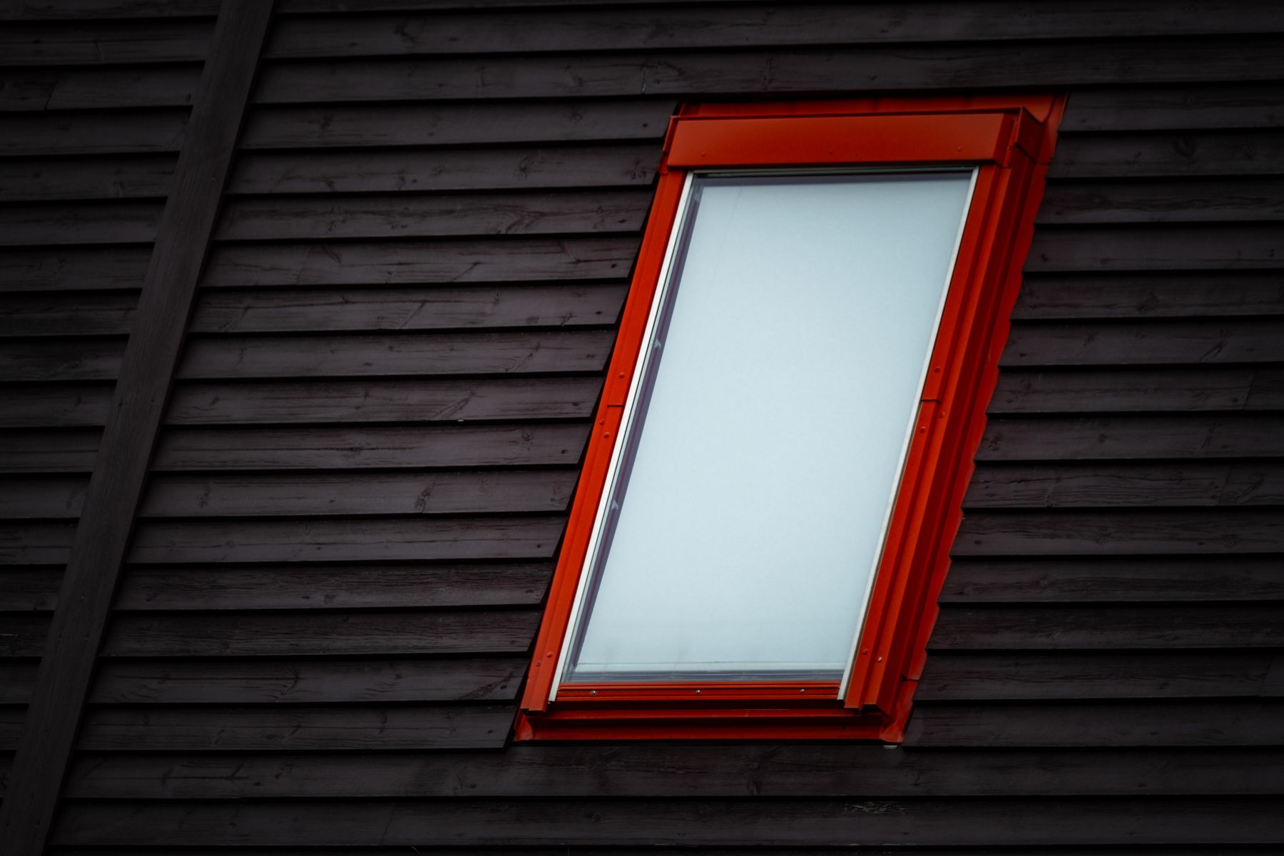Rot gerahmtes Dachfenster in einer dunklen Holzverkleidung